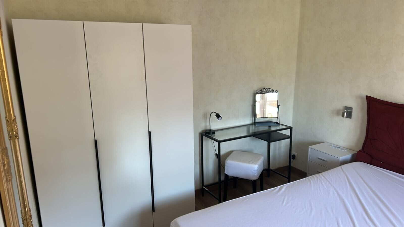 Een slaapkamer met een bed, een bureau met stoel, een kledingkast en een nachtkastje.