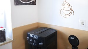 Een koffieapparaat, een glas en een muur met kunst en tekst over koffie.