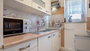 Een keuken met een magnetron, spoelbak en kastjes.