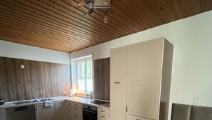 Une cuisine spacieuse avec un plancher en bois, un four encastré et un grand placard blanc.