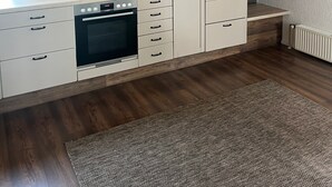 Une cuisine moderne avec des meubles en bois, un four encastré et une grande fenêtre.