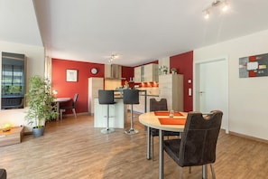 Una cucina moderna con zona pranzo, pavimento in legno e parete decorata a rosso.