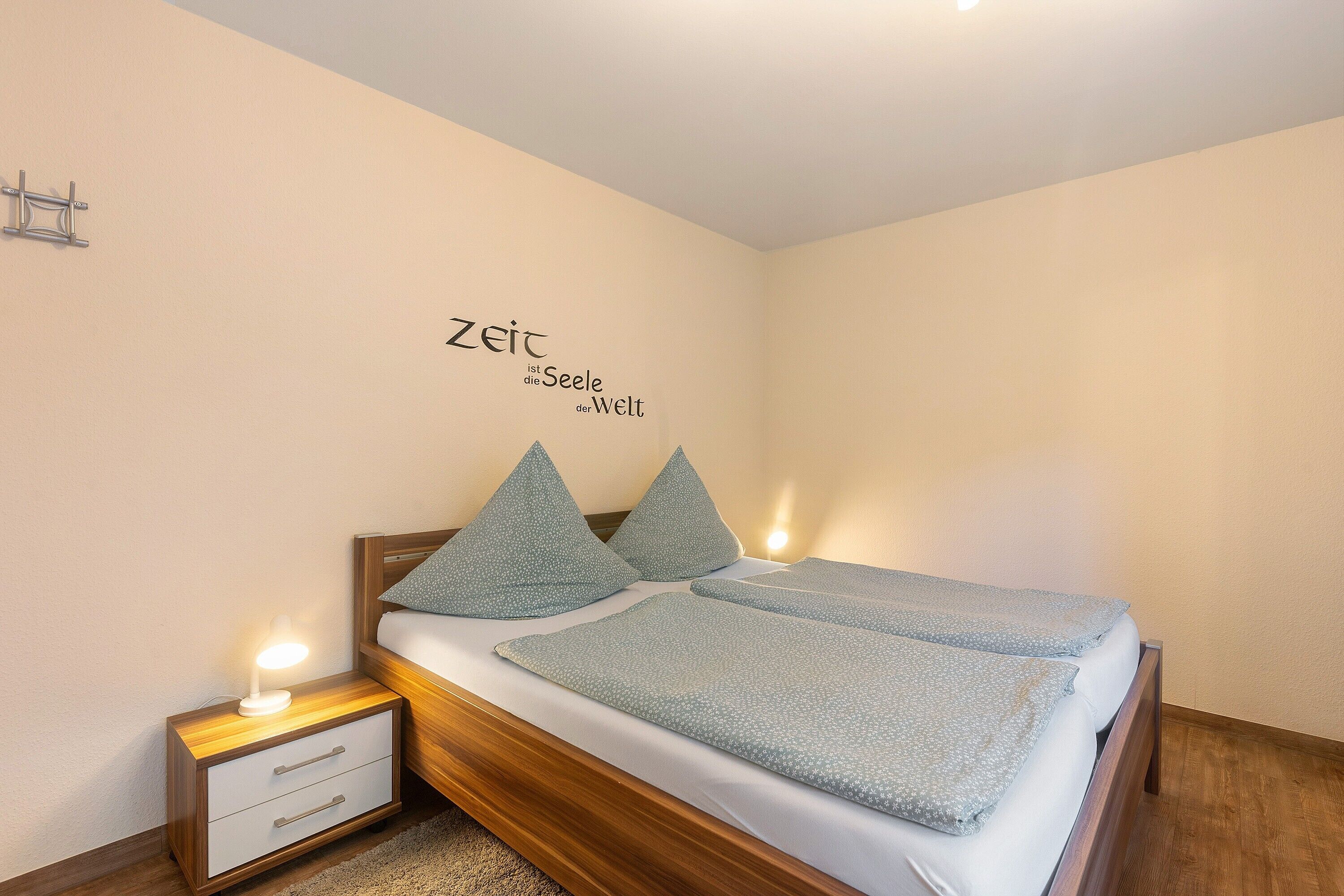 A neatly made bed with pillows and a bedside table with a lamp.