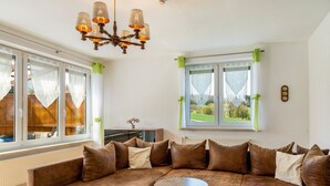 A living room with a sectional sofa, a small round table, and a chandelier.