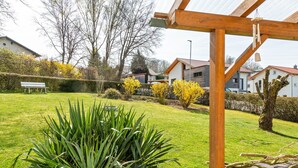A garden with a wooden pergola, a bench, and a variety of plants.