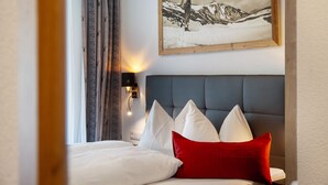 Une chambre d’hôtel avec un lit, une tête de lit, un tableau accroché au mur et une table de chevet avec une lampe.