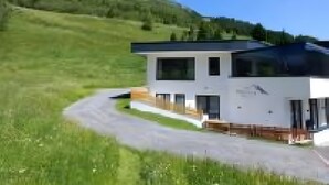 Une maison moderne à deux étages, avec une allée menant à l’entrée.