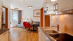 Une cuisine moderne dotée d’un four encastré, d’un évier en acier inoxydable et d’un coin repas avec une table et des chaises.