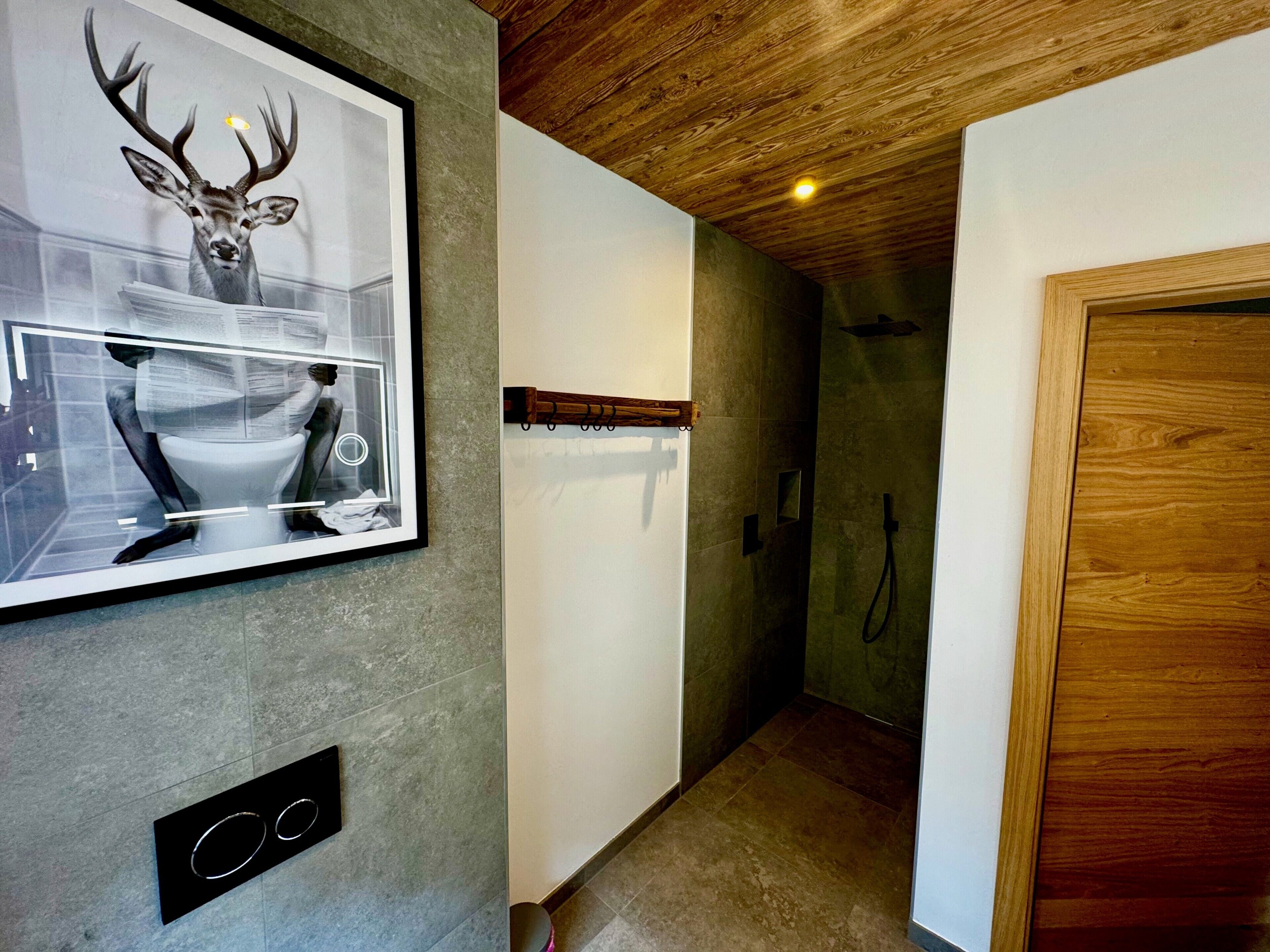 Une salle de bain moderne avec un grand tableau encadré représentant un cerf, un miroir et un espace douche.