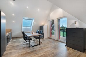 A modern kitchen with a dining area, a large window, and a view of the outdoors.