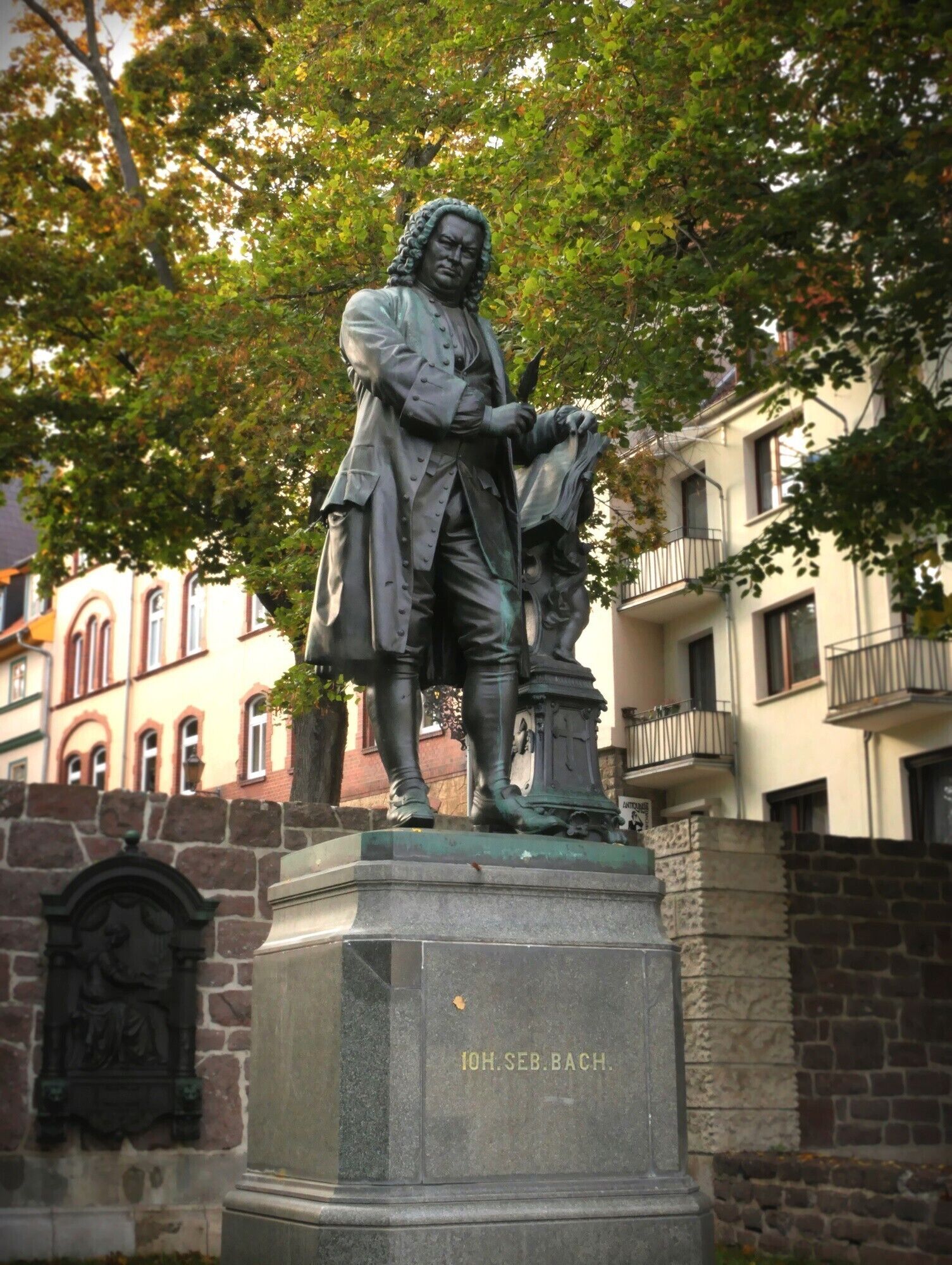Una statua di una figura storica con una targa che riporta '10H. SEB. BACH'.
