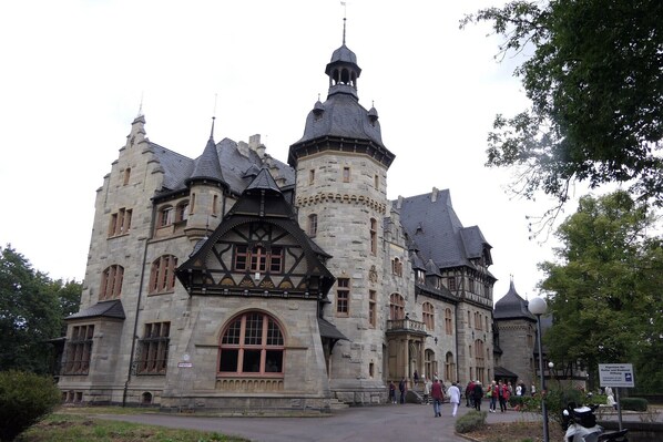 A historic building with a turreted tower, large arched windows, and a stone facade.