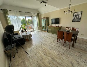 A living room with a sofa, dining table, chairs, a TV, and a chandelier.