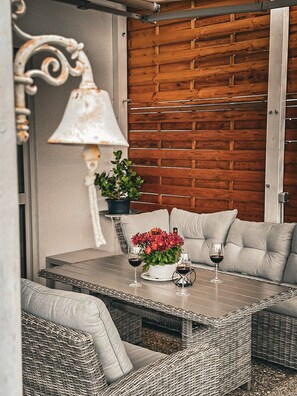 A wicker table with two cushions, a potted plant, and two wine glasses.