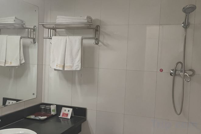 A bathroom with a sink, mirror, towel rack, and shower.