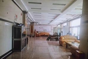 Um hall amplo com um balcão de recepção extenso, um sofá grande e um mapa na parede.