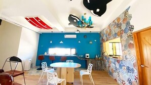 A dining area with a round table, white chairs, a blue accent wall, and a ceiling with black and white decor.