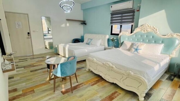 A bedroom with a large bed, a small table, and a chair.