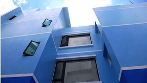 A building with a blue facade, multiple windows, and a geometric design.