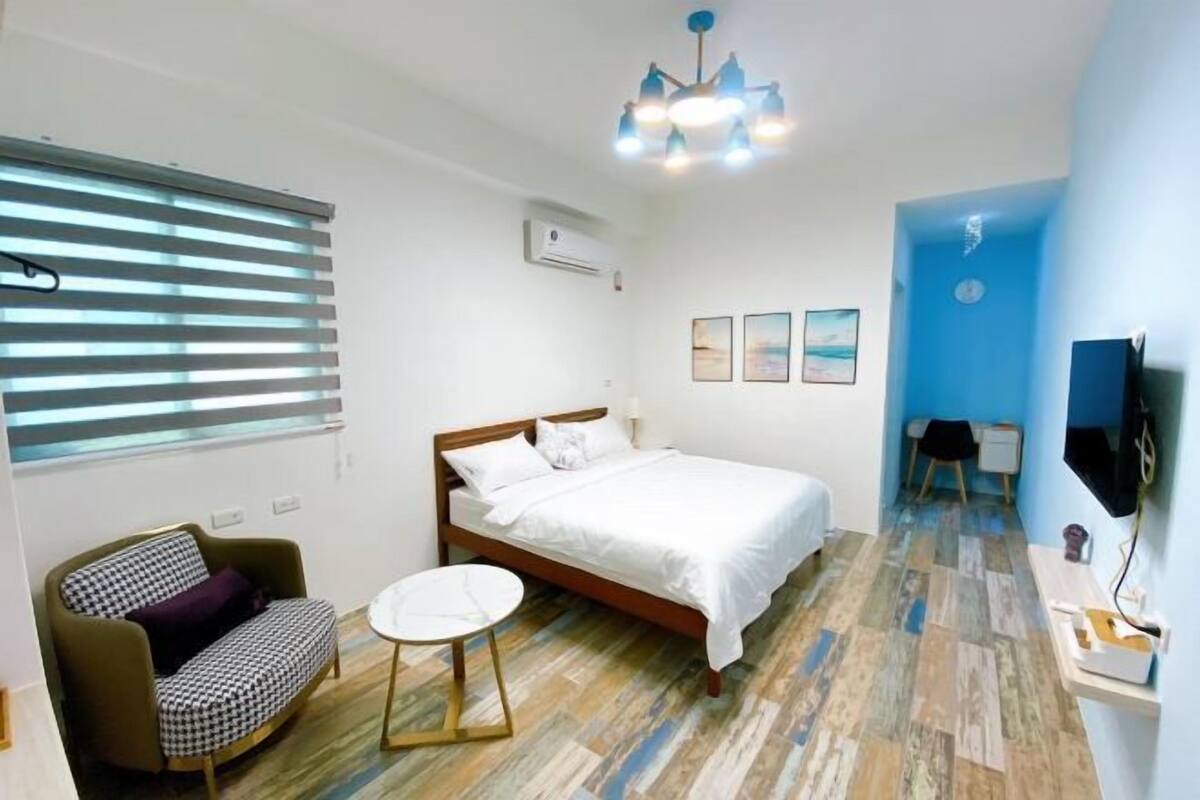 A bedroom with a bed, a sofa, a small round table, and a TV.