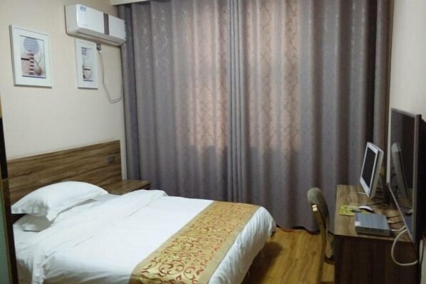 A hotel room with a bed, a desk with a computer, and a window with curtains. - Xinye Jinchen Business Hotel (Xinye)