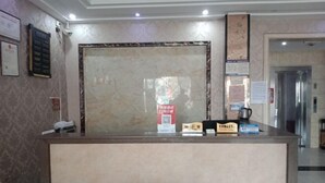 A reception desk with a marble counter, framed certificates on the wall, and a coffee machine. - Xinye Jinchen Business Hotel (Xinye)