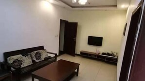 Un salon avec un canapé, une table basse, un téléviseur et une porte.