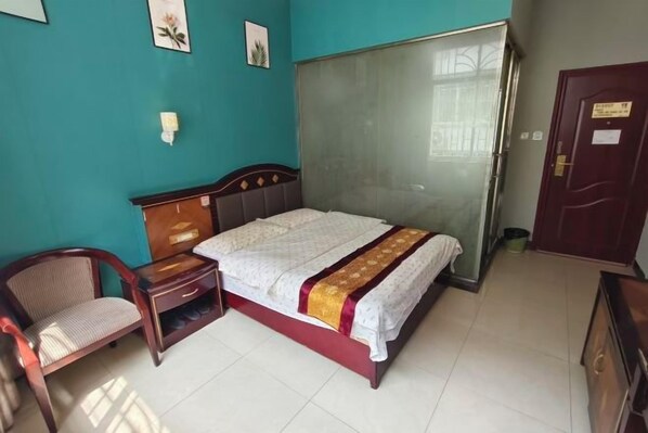Un dormitorio con cama, una silla, un armario y una mesita.