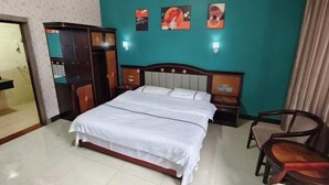 Une chambre d’hôtel avec un lit, des tables de chevet, une armoire et des œuvres d’art accrochées au mur.
