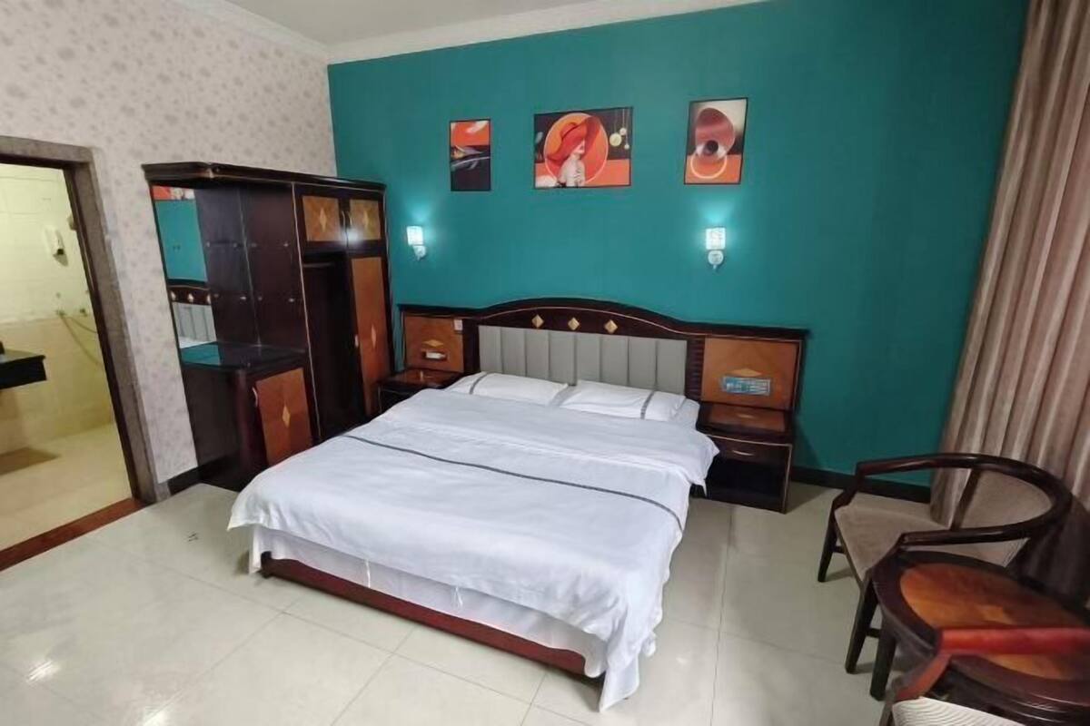 Een hotelkamer met een bed, nachtkastjes, een kledingkast en kunst aan de muur.