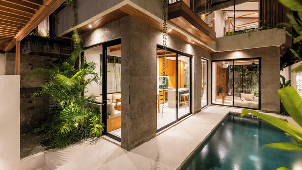 A modern house with a swimming pool, large windows, and indoor plants.