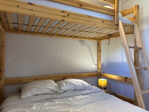 Un lit superposé avec une échelle, une lampe de chevet et une tête de lit.