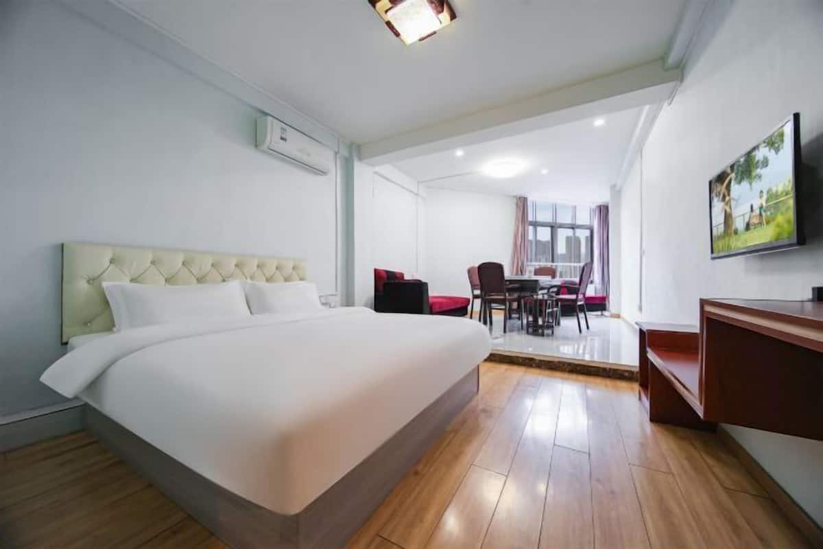 Une chambre d’hôtel dotée d’un grand lit, d’un coin repas avec des chaises et une table, d’un téléviseur fixé au mur et d’un appareil de climatisation.
