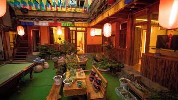 A courtyard with a pool table, wooden benches, and potted plants.