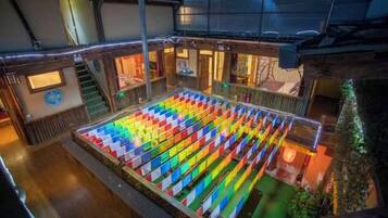Un amplio espacio interior con una gran disposición de asientos coloridos y una escalera que conduce a un nivel superior.