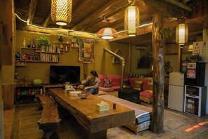 Un salon chaleureux avec une table en bois, des étagères et un téléviseur.