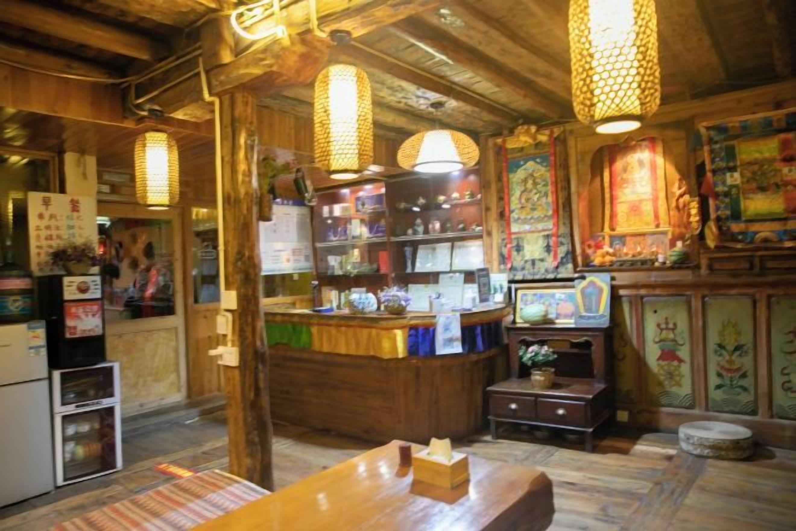 A traditional Japanese restaurant interior with wooden beams, hanging paper lanterns, a counter with a menu, and a small shrine area.