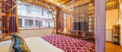 Una habitación con una cama, un ventanal grande y techo de madera.
