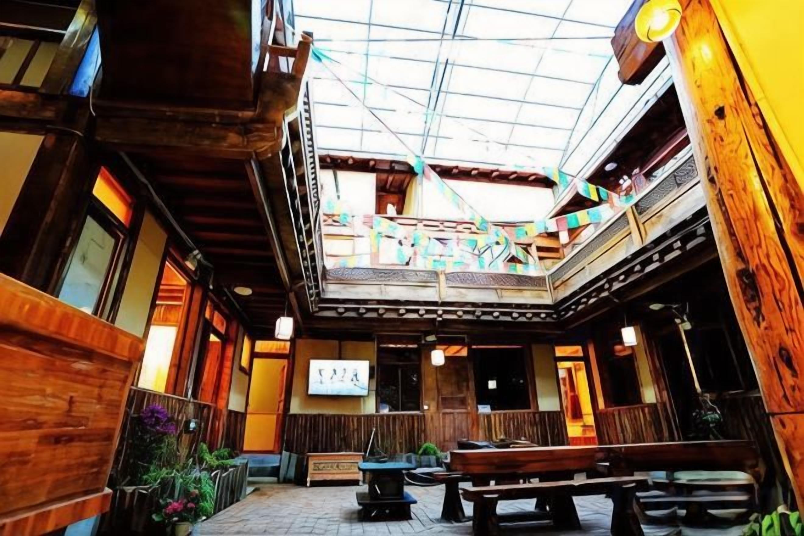 An indoor courtyard with wooden benches, a glass ceiling, and a signboard.