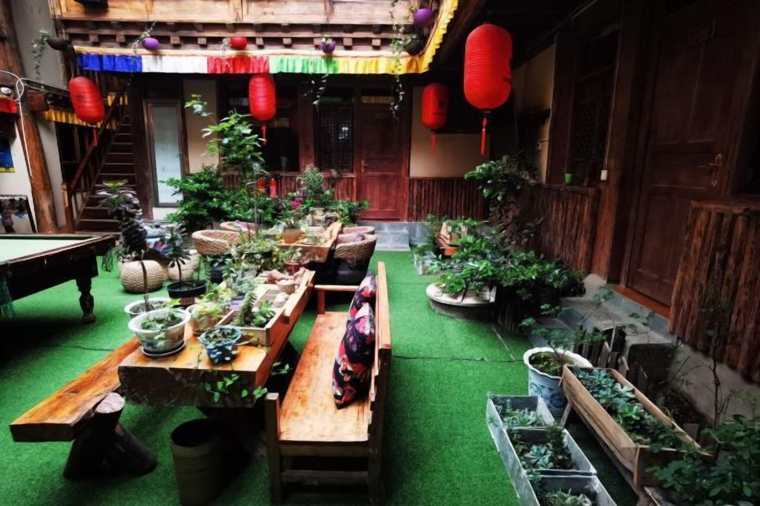 A courtyard with a wooden table, potted plants, and a bench.