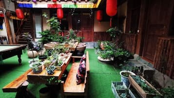 A courtyard with a wooden table, potted plants, and a bench.