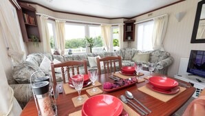 Comedor con una mesa de madera dispuesta para cuatro personas, rodeado de sofás con motivos.