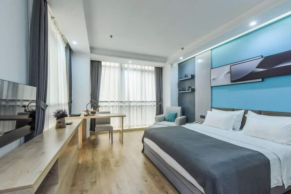 A modern hotel room with a bed, desk, chair, and a TV.