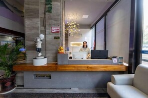 Een receptiebalie met een receptionist, een beeld en een modern interieur.