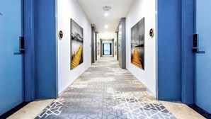 A modern hallway with blue walls, geometric patterned floor, and framed artwork on the walls. - Hotel & Davos (Chongqing Ranjiaba Light Rail Station) (Chongqing)