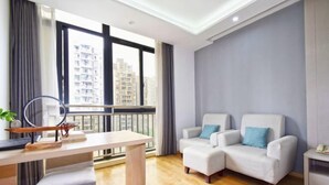 A modern living room with a balcony, a dining table, two armchairs, and a small side table. - Hotel & Davos (Chongqing Ranjiaba Light Rail Station) (Chongqing)