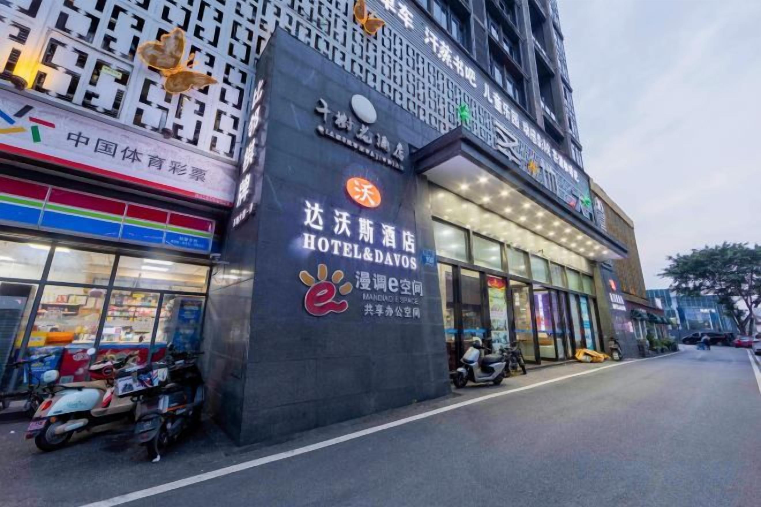 A hotel with a prominent sign, a covered entrance, and a row of parked scooters.