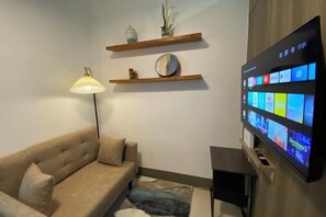 Olohuone, jossa on sohva, lamppu, litteänäyttöinen televisio ja puuhyllyt.