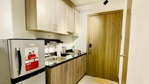 Una cocina compacta con armarios de madera, un refrigerador de acero inoxidable y un lavamanos.