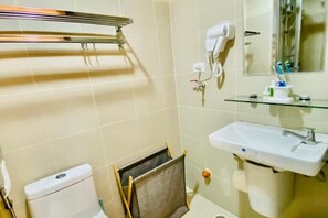 A bathroom with a toilet, sink, and towel rack. - Gavin's Place @ FAME Residences (Mandaluyong)